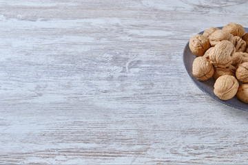 Ceramic plate with nuts on white wood.