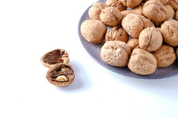 Walnuts in a bamboo bowl on a white board.