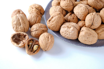 Walnuts in a bamboo bowl on a white board.