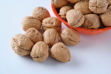 Walnuts in a bamboo bowl on a white board.