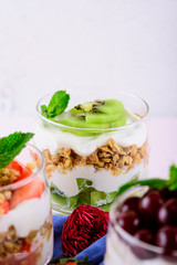 vertical crop image of dessert with strawberries, cherries, kiwi, cream, granola and mint