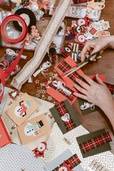 View of hands of young woman on table making handmade Christmas cards with Snowman and Santa