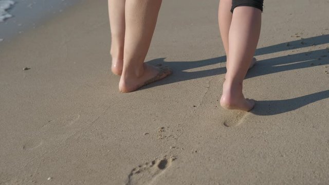Family with bare foot walks at the sea.