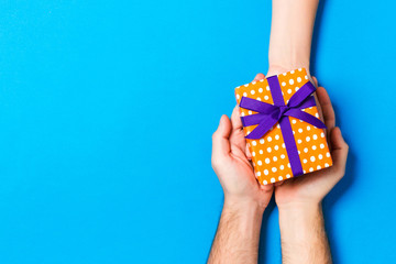 Top view of a woman and a man giving and receiving a present on colorful background. Love and relationship concept. Copy space