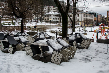 Coffee shop chairs and tables, covered in snow in winter, Smolyan, Bulgaria. Winter in the city