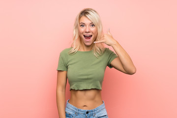 Obraz na płótnie Canvas Young blonde woman over isolated pink background making phone gesture. Call me back sign