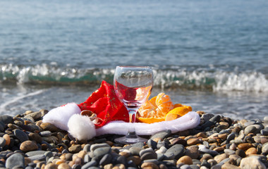 Exotic new year and Christmas at sea. Bottle and drinking glasses on sea beach. wine drink, santa claus hat at seaside symbolizing celebration of new year in hot climate or weather.