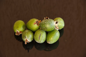 Fresh fruits of feijoa on a glass table with a reflection