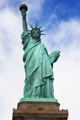 Obraz premium Statue of Liberty from below with blue sky and clouds on American Liberty Island in New York City, USA