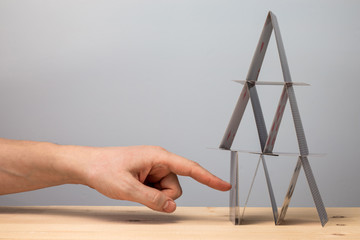 Hand breaks the house of cards