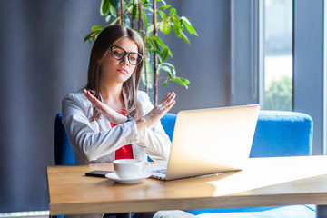 Closed. this is the end. Portrait of serious young woman in glasses sitting, looking at her laptop...