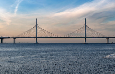 Fototapeta na wymiar Cityscape - View of cable-stayed bridge and bay on a frosty day at sunset, golden lighting