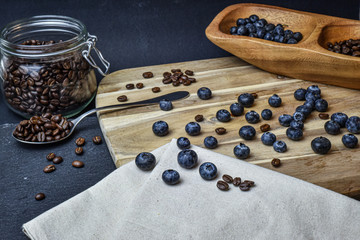 Fresh Blueberries and coffee beans on a black slate and wooden background
