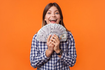 Portrait of wealthy attractive brunette woman wearing checkered shirt holding dollar bills and...