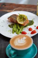 A coffee cups with a coffee latte and delicious salmon for breakfast at the café