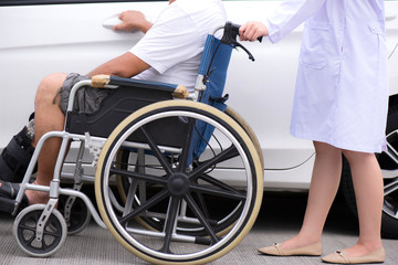 Obraz premium A senior man sitting on a wheelchair.Open the car door on the road, with a nurse pushing a wheelchair in the back