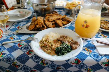 plate with beans, rice and beef and a carafe of orange juice