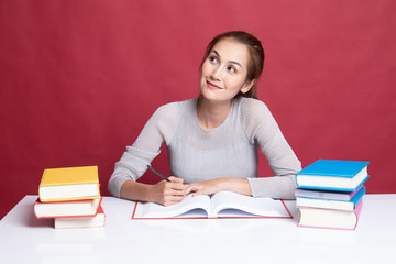 Young Asian woman read a book with books on table.