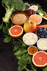 Healthy food clean eating selection: fruit, vegetable, seeds, superfood, cereals, leaf vegetable on rustic background
