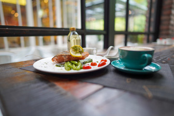 A coffee cups with a coffee latte and delicious salmon for breakfast at the café