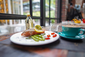A coffee cups with a coffee latte and delicious salmon for breakfast at the café