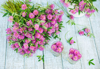 Traditional Herbal Tea of Red Clover Flowers (Trifolium pratense). Fresh Clover Flower Tea in the glass cups. Purple Wildflowers bouquet on a wooden rustic table. Phytotherapy Medicinal Herbs
