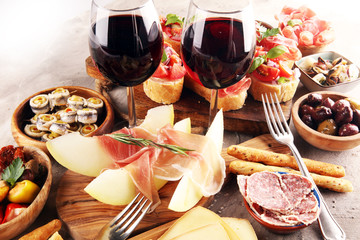 Fototapeta na wymiar Italian antipasti wine snacks set. Cheese variety, Mediterranean olives, seafood salad, Prosciutto di Parma, tomatoes, anchovy and wine in glasses