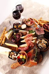 Italian antipasti wine snacks set. Cheese variety, Mediterranean olives, seafood salad, Prosciutto di Parma, tomatoes, anchovy and wine in glasses