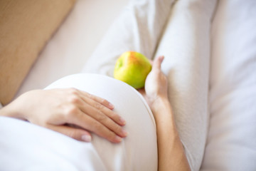 Pregnancy. Healthy food - pregnant woman with green apple at home