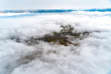 views of a population between clouds and fog below during a hot air balloon flight in Cerdanya, Catalonia