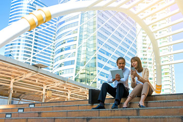 Businesspeople using tablet and mobile while sitting on the stai