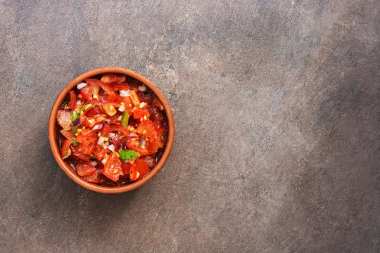 Traditional mexican homemade salsa sauce on a dark rustic background. Top view, flat lay, copy space.