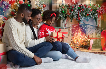 Obraz premium Adorable little afro girl received Christmas present from her parents