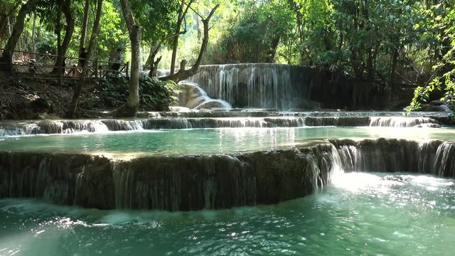 Static Wideshot of Kuang Si Waterfall during Sunny Weather and Tourist Taking Selfie