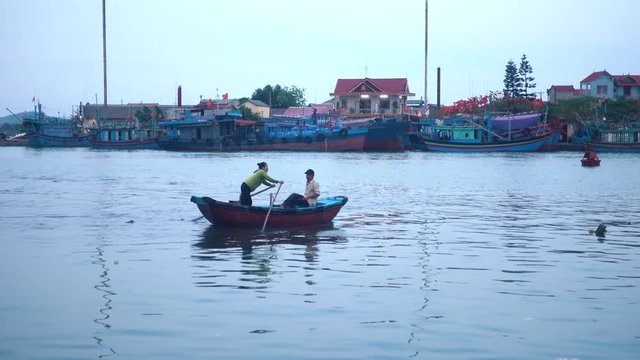 Wideshot of Two People in a Rowboat in a Small Vietnamese Fishing Village