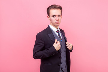 Portrait of arrogant businessman in expensive suit and with stylish haircut holding his tuxedo,...