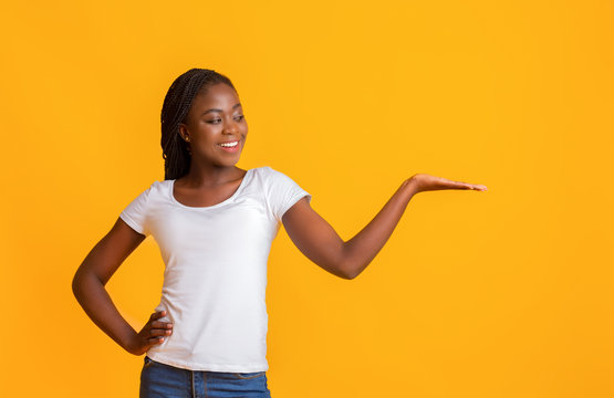 Smiling woman with her palm up over yellow background