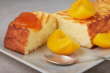 A portion of cottage cheese casserole with strawberry jam and peaches