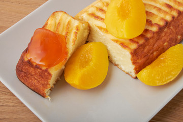 A portion of cottage cheese casserole with strawberry jam and peaches