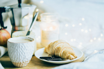 Cozy winter weekend breakfast, coffee and croissant on wooden tray