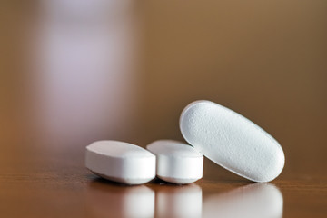 Close -up of three pills with oval shape on a table, selective focus