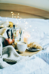 Fototapeta na wymiar Cozy winter weekend breakfast, coffee and croissant on wooden tray