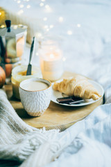 Cozy winter weekend breakfast, coffee and croissant on wooden tray