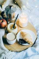 Cozy winter weekend breakfast, coffee and croissant on wooden tray