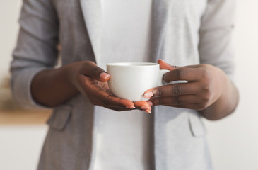 Cup of coffee in hands of unrecognizable black businesswoman