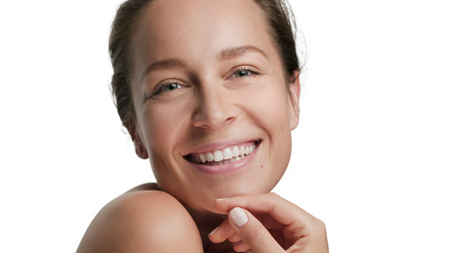 Close-up beauty portrait of young smiling woman with smooth healthy skin on white background