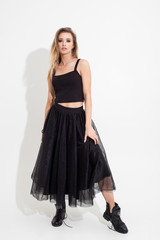 Fototapeta premium Girl in t-shirt and black skirt posing on a white background. Fashion shooting