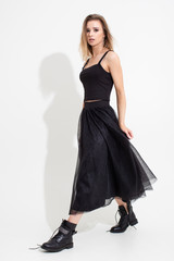 Naklejka premium Girl in t-shirt and black skirt posing on a white background. Fashion shooting
