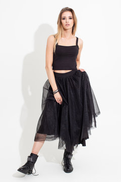 Girl in t-shirt and black skirt posing on a white background. Fashion shooting