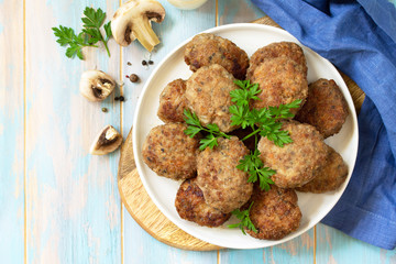 Homemade meatballs with mushrooms on the kitchen wooden table. Top view of a flat lay. Copy space.